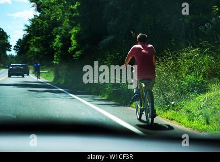A driver`s view of young men on bicycles utilizing the roads bike lanes on a nice sunny day. Stock Photo
